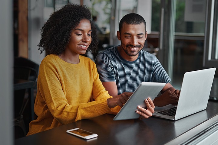 Couple using a tablet and laptop in café