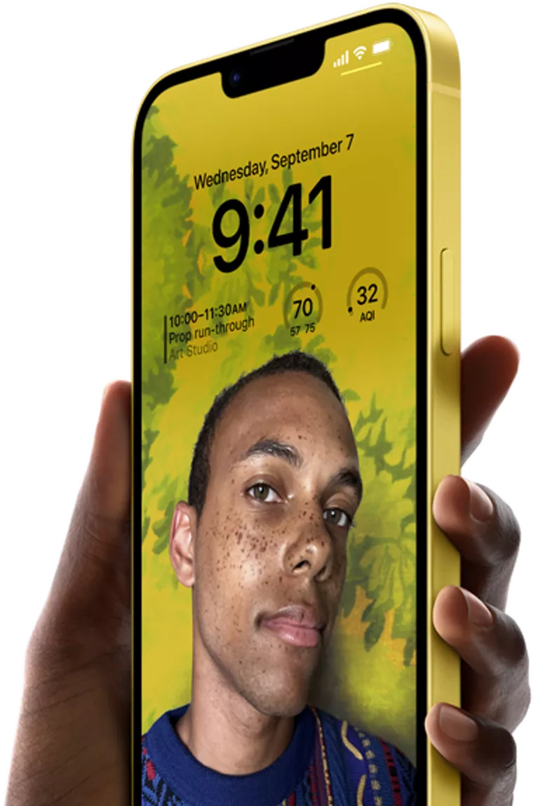 Una mano sostiene al iPhone 14 Plus en amarillo con un bloqueo de pantalla personalizado.