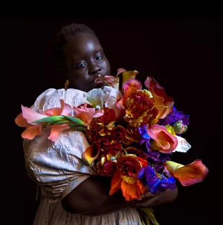 Foto con poca luz de una persona sosteniendo un colorido ramo de flores.