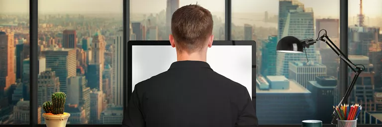 Man working from home looking from a tall building with a view of the city